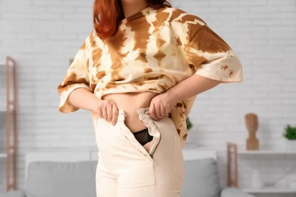 Image of woman trying to do her trousers up after pregnancy weight gain East Malling